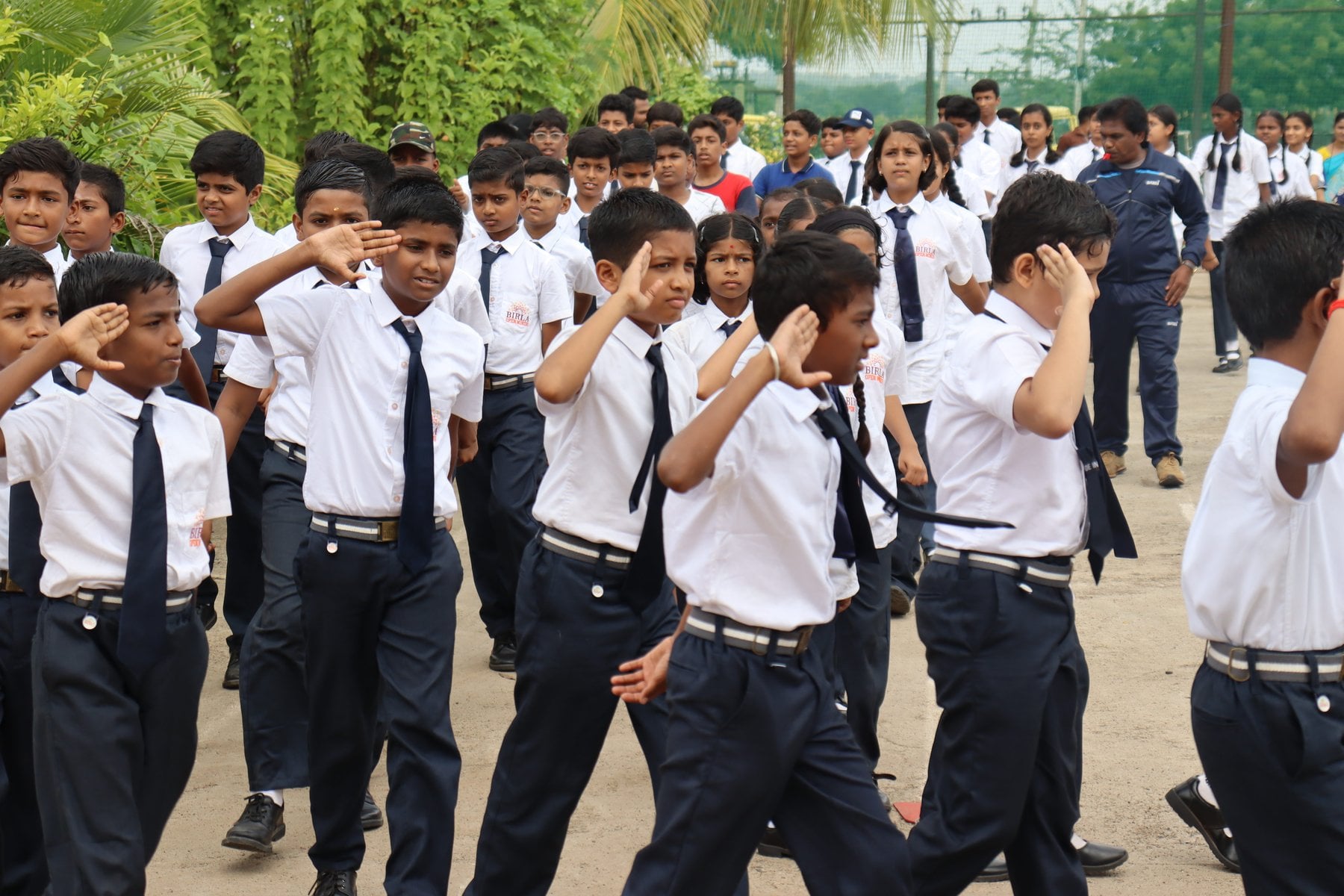 Students of SHLOKA - A Birla School in uniform, saluting as they march past on the school grounds